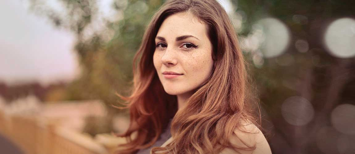 Sfeerafbeelding van een vrouw in de natur die naar de fotograaf kijkt